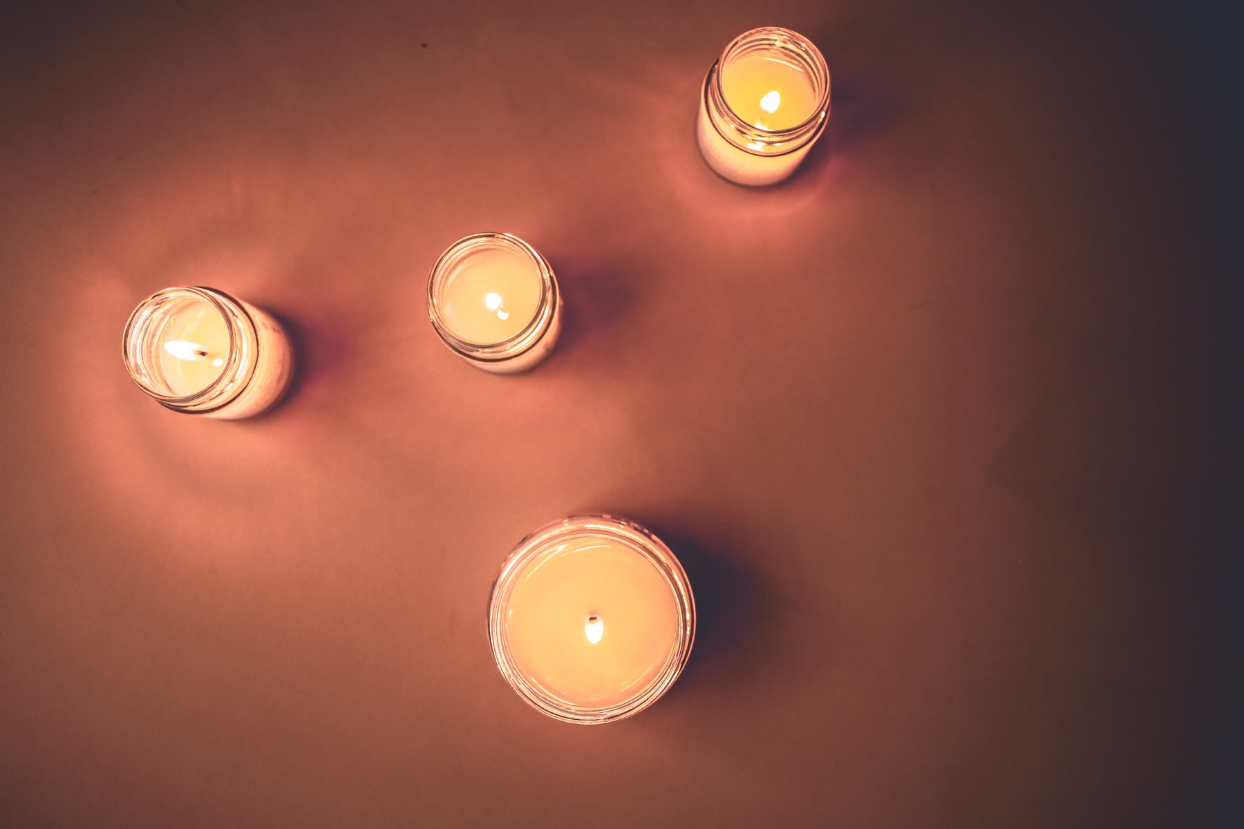 Four lit candles in dark orange background